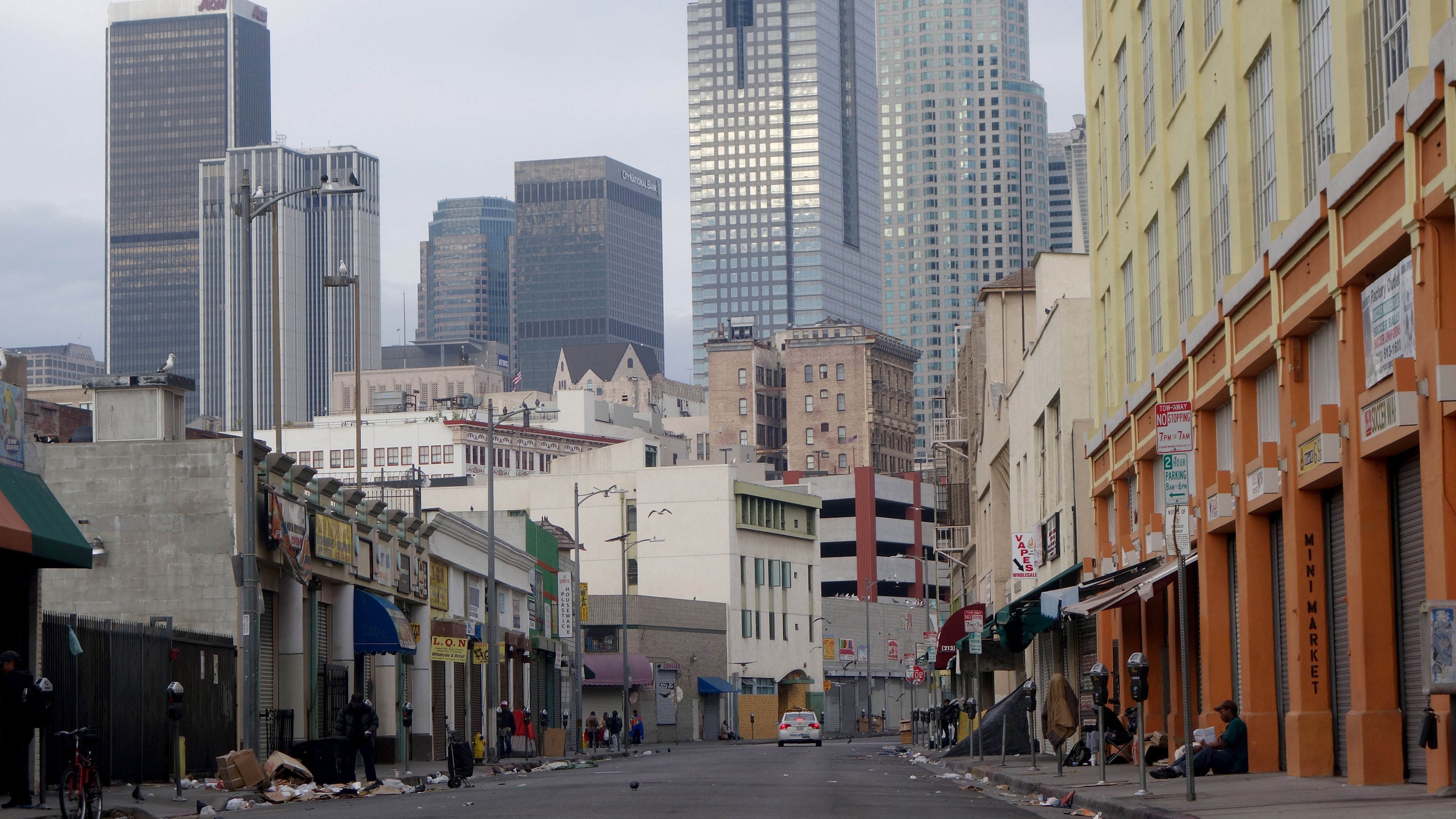 Homeless people on 'Skid Row' Los Angeles with the wealthy skyscrapers of the city above