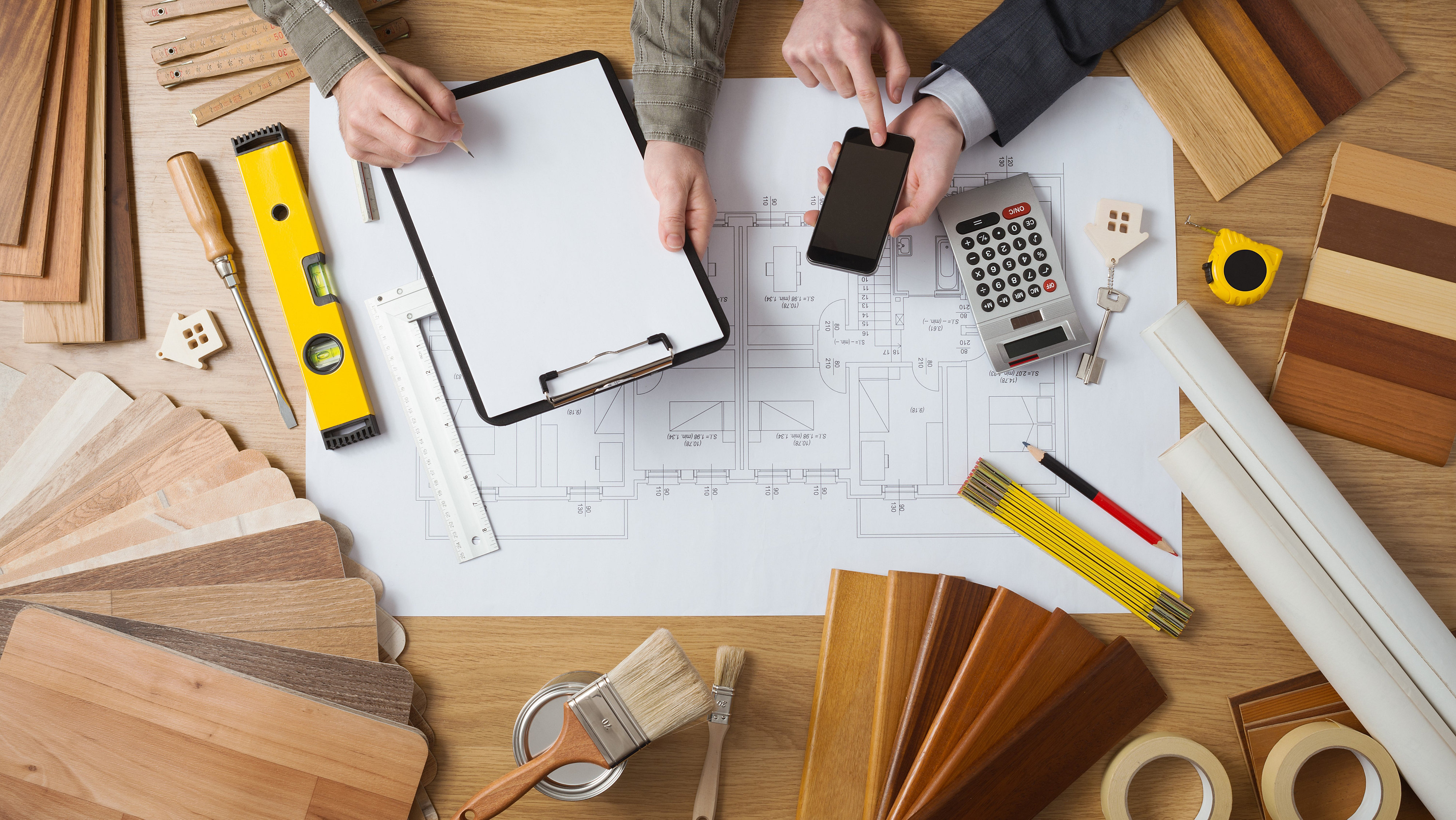 Aerial shot of men working at desk with plans and surveying tools