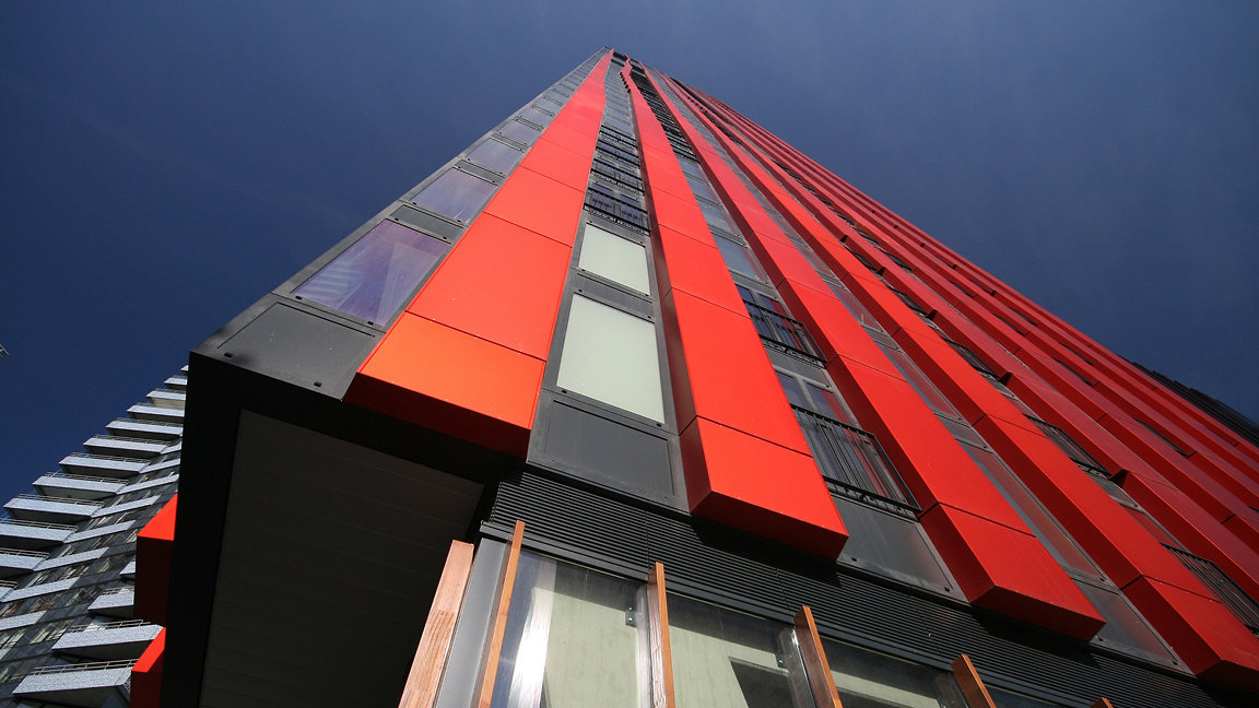 Tall building with vertical red panels, shot from low level looking up