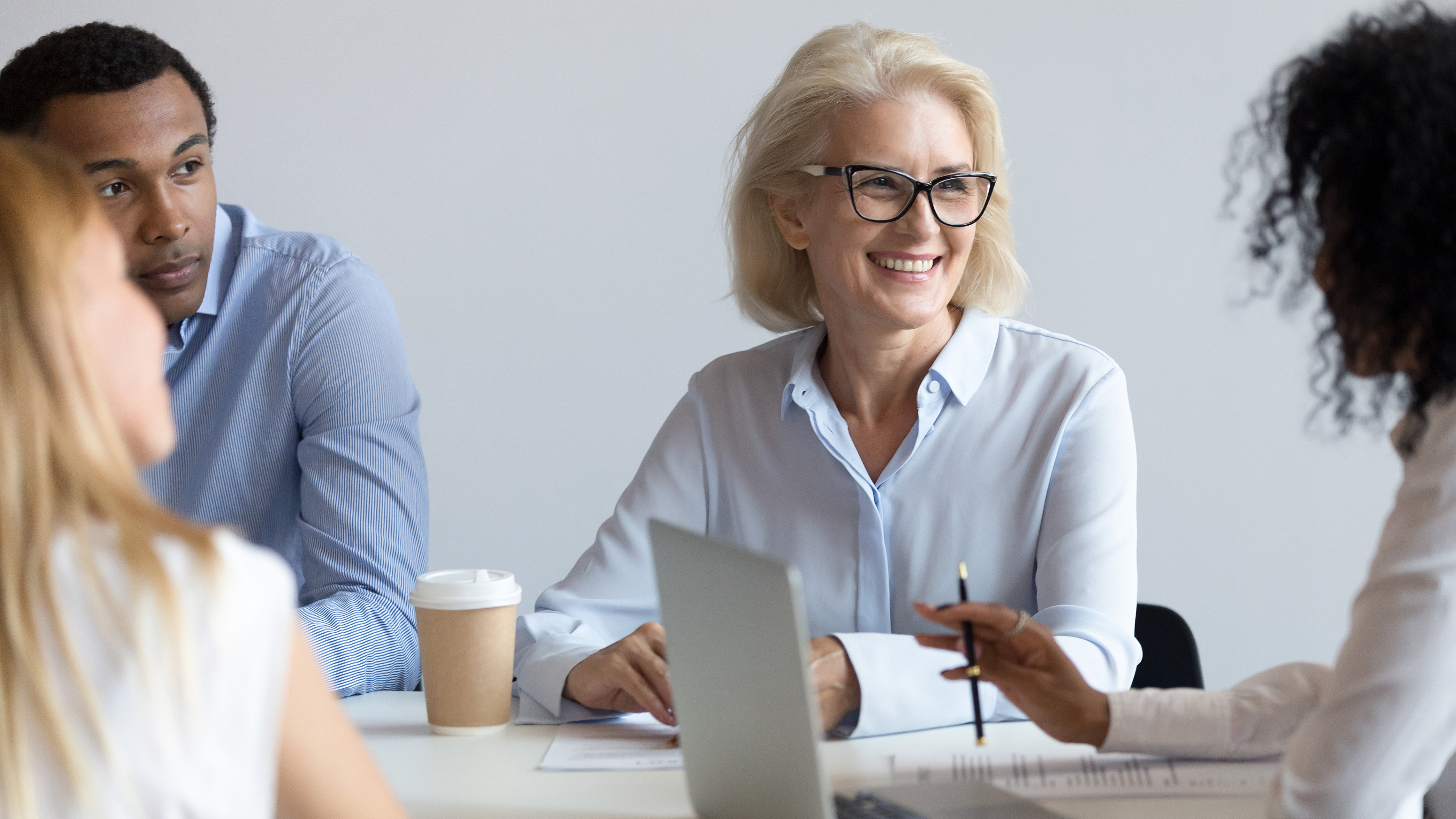 3 women and a man around a meeting table having a discussion