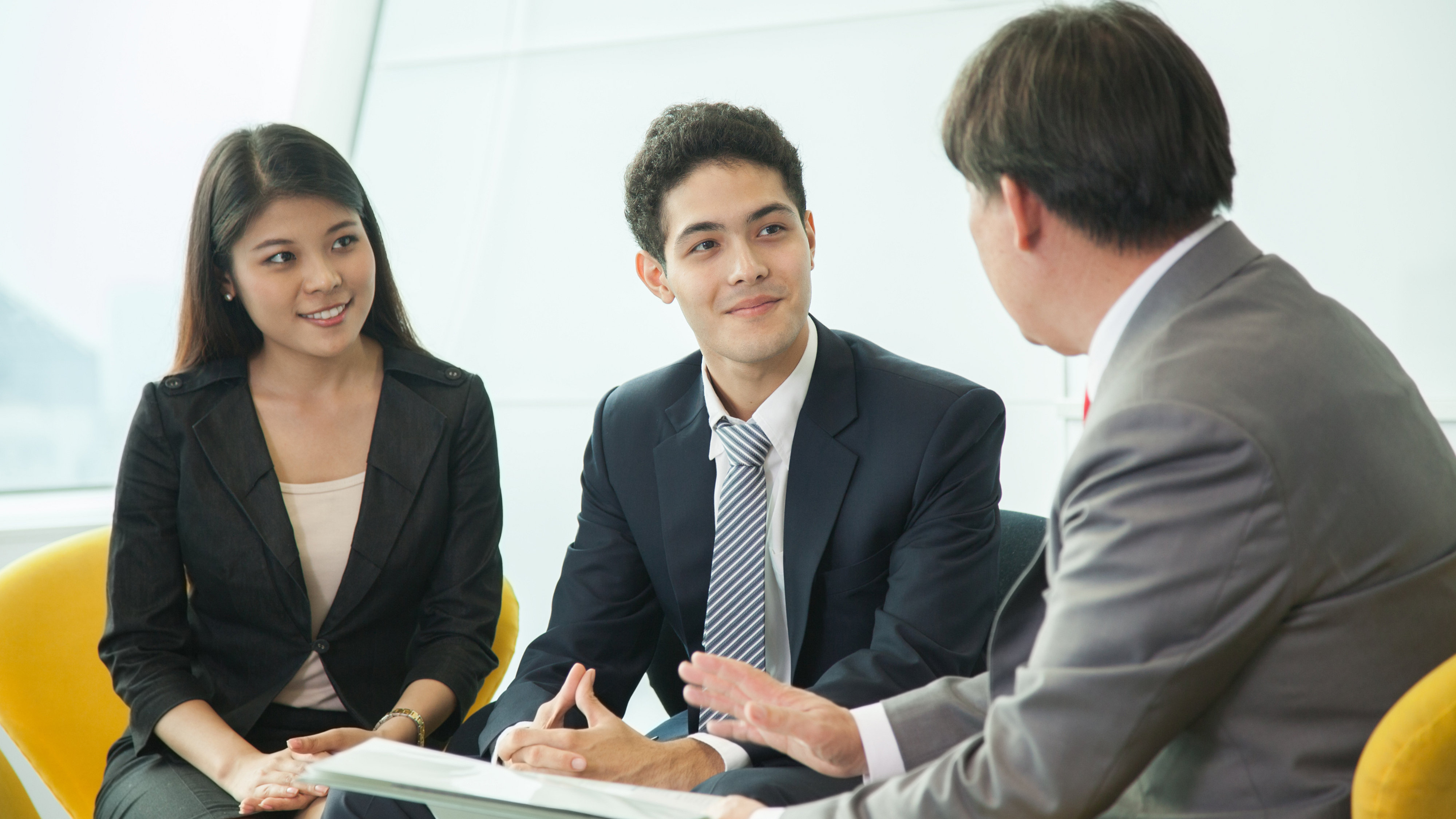 Man advising male and female business people seated on sofa