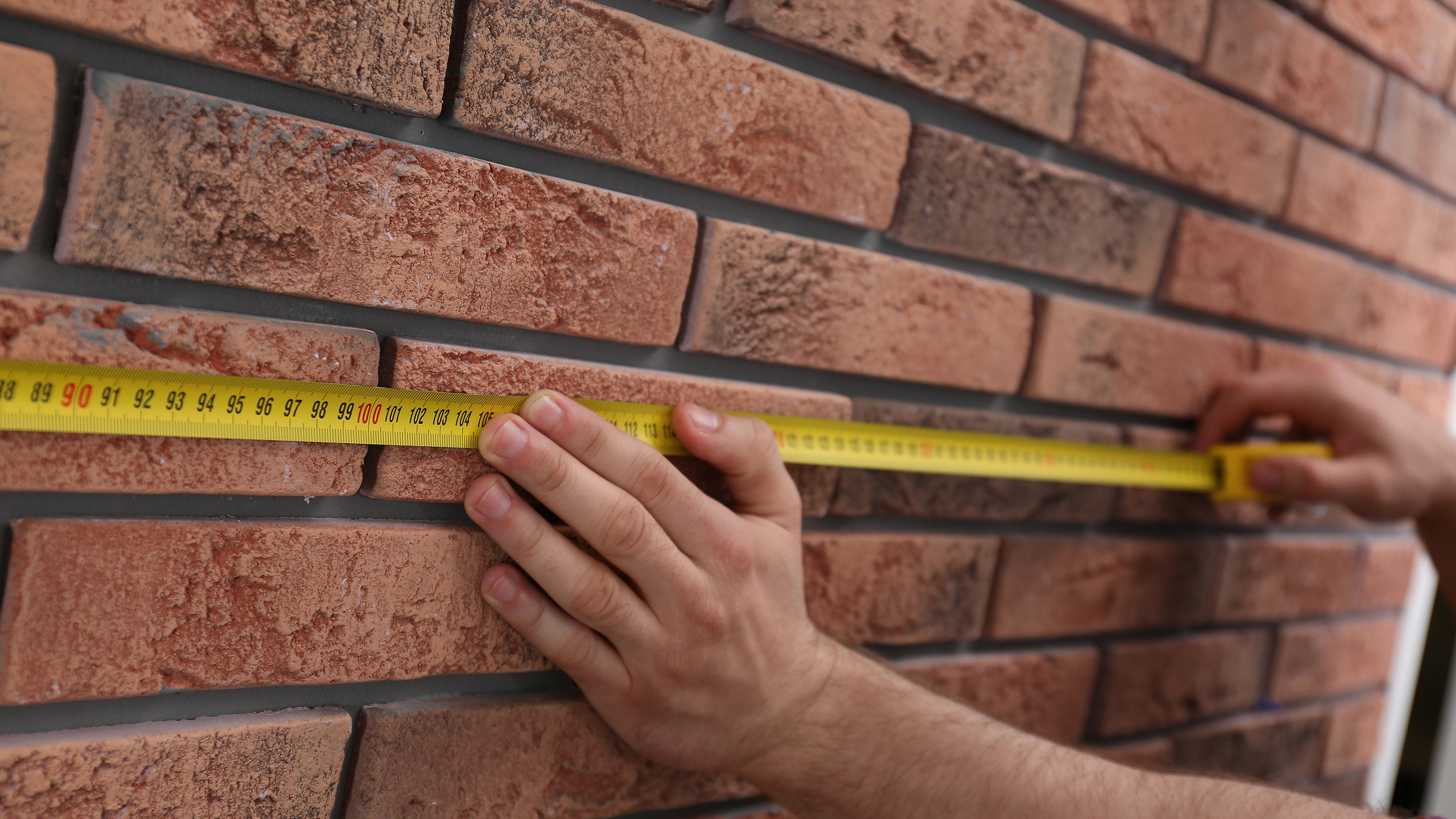 Photo of surveyor measuring building with measuring tape