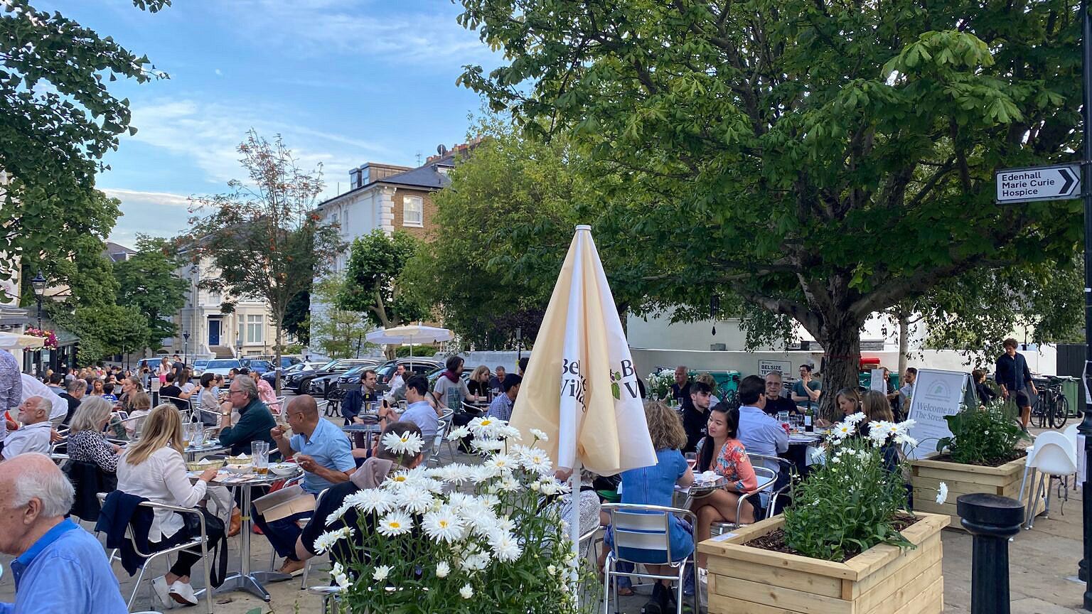 People eating outdoors in summer at a pavement restaurant in Belsize Park, London. Image © Belsize Village Business Association