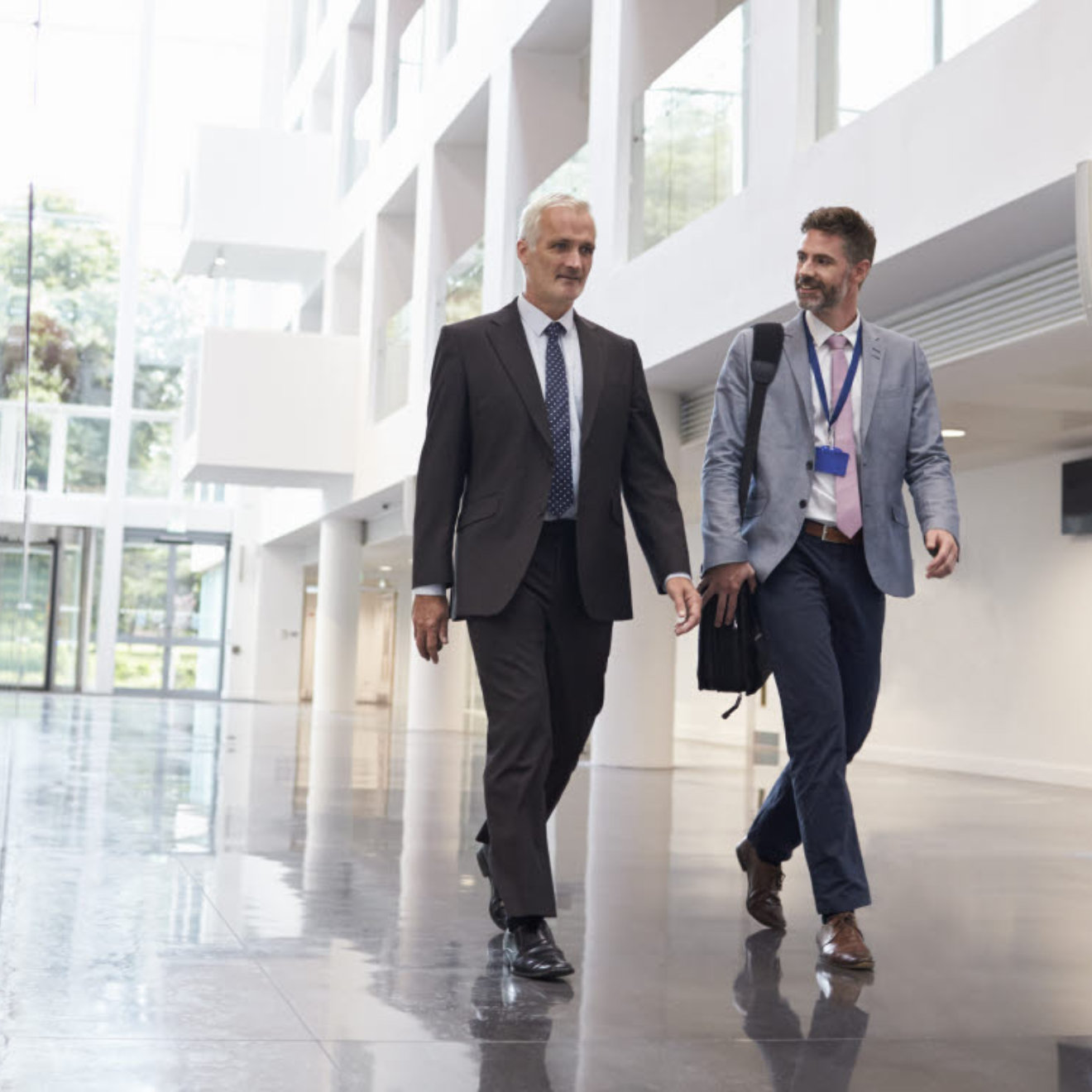 Two_men_walking_through_a_modern_office_lobby