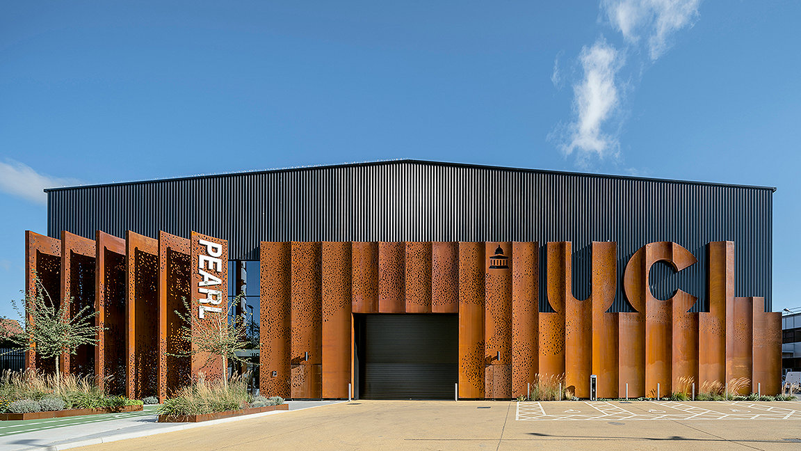 Front of large warehouse building with weathered steel cladding against blue sky