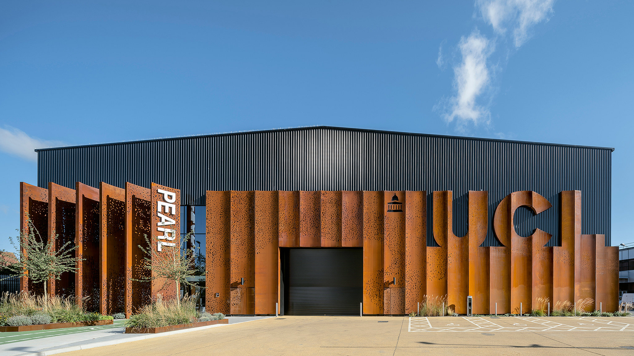 Front of large warehouse building with weathered steel cladding against blue sky