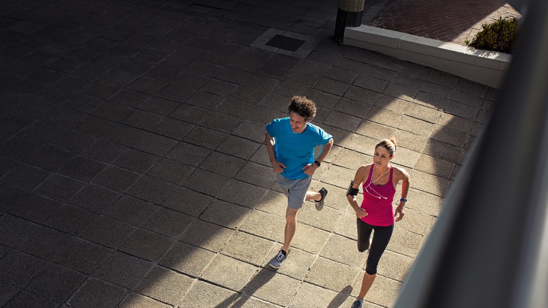 Couple making fitness and jogging in the urban area of the city. High angle view of two mature people training together on road. Fitness man and woman running on city street.; Shutterstock ID 1238296123; Purchase Order: N/A