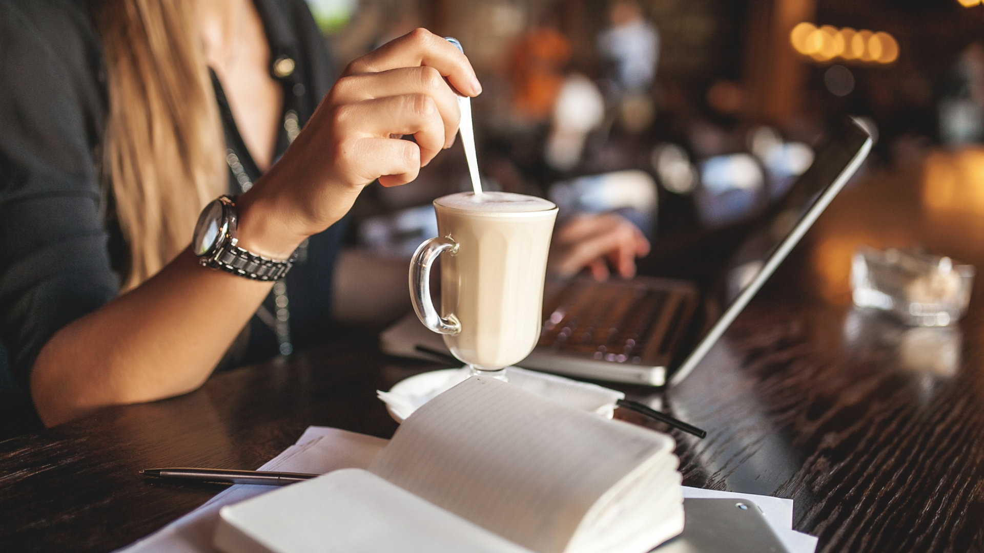 Woman working in public cafe stirring a coffee