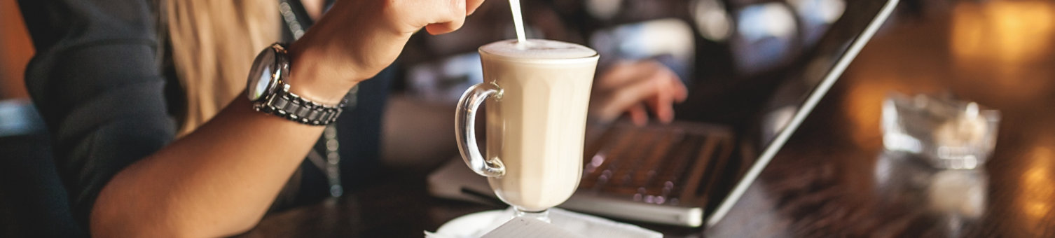 Woman working in public cafe stirring a coffee