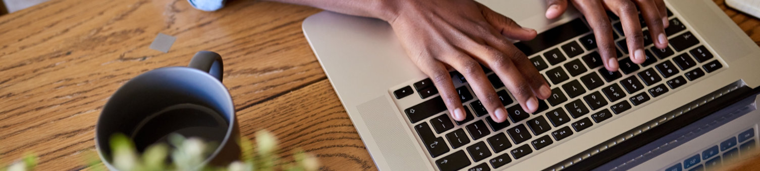 Closeup of an African American female entrepreneur working online with a laptop while sitting at a table at home  ; Shutterstock ID 1317157079; Purchase Order: N/A