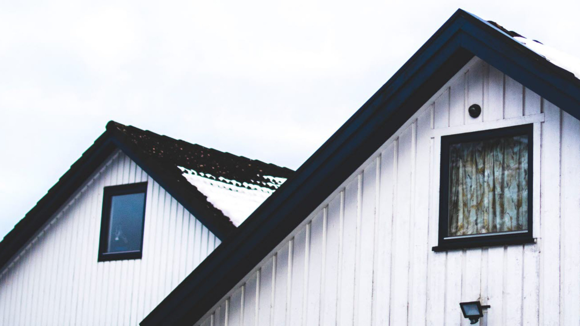 The gable end of a white home with a black roof