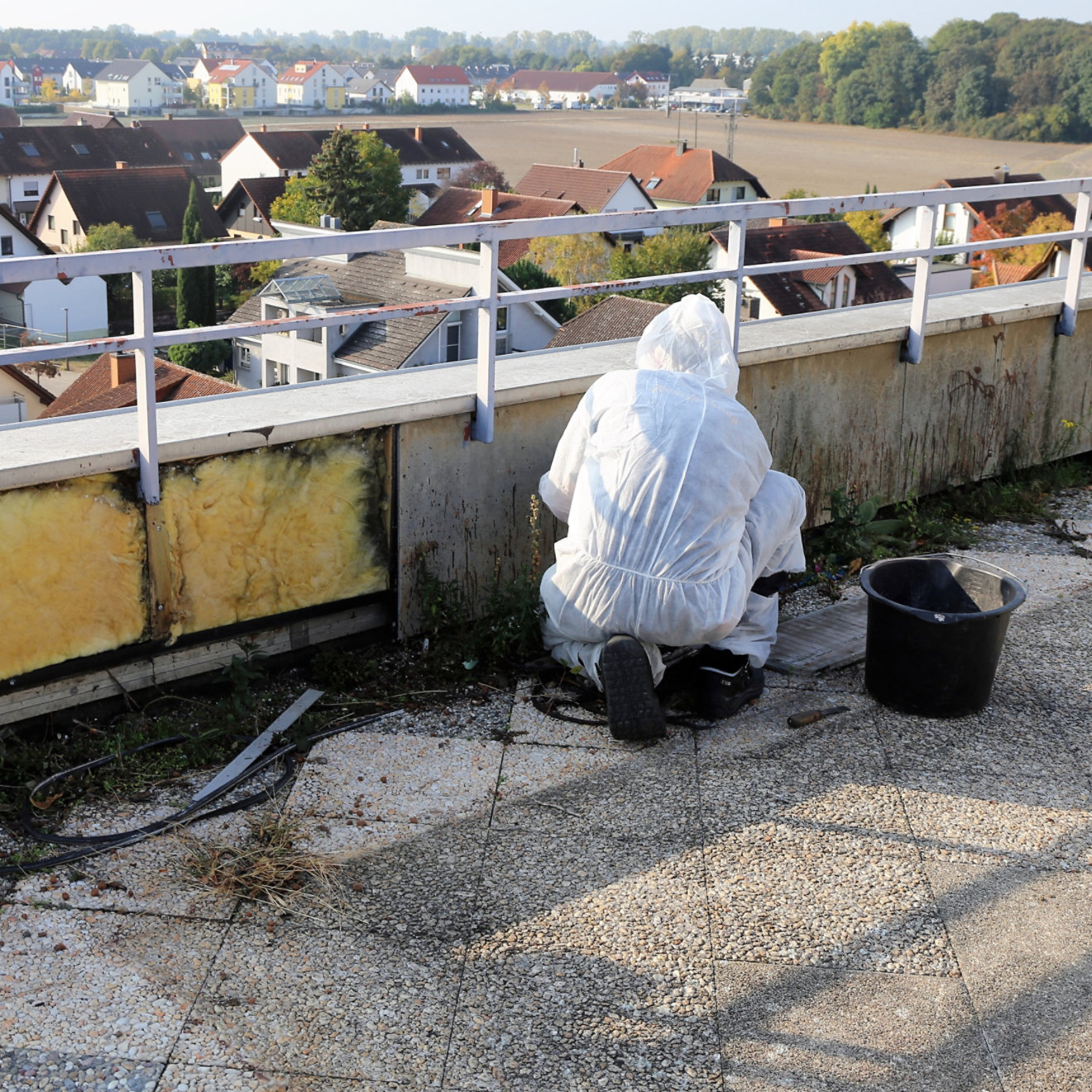 Man cleaning asbestos on a roof in a hazard suit.