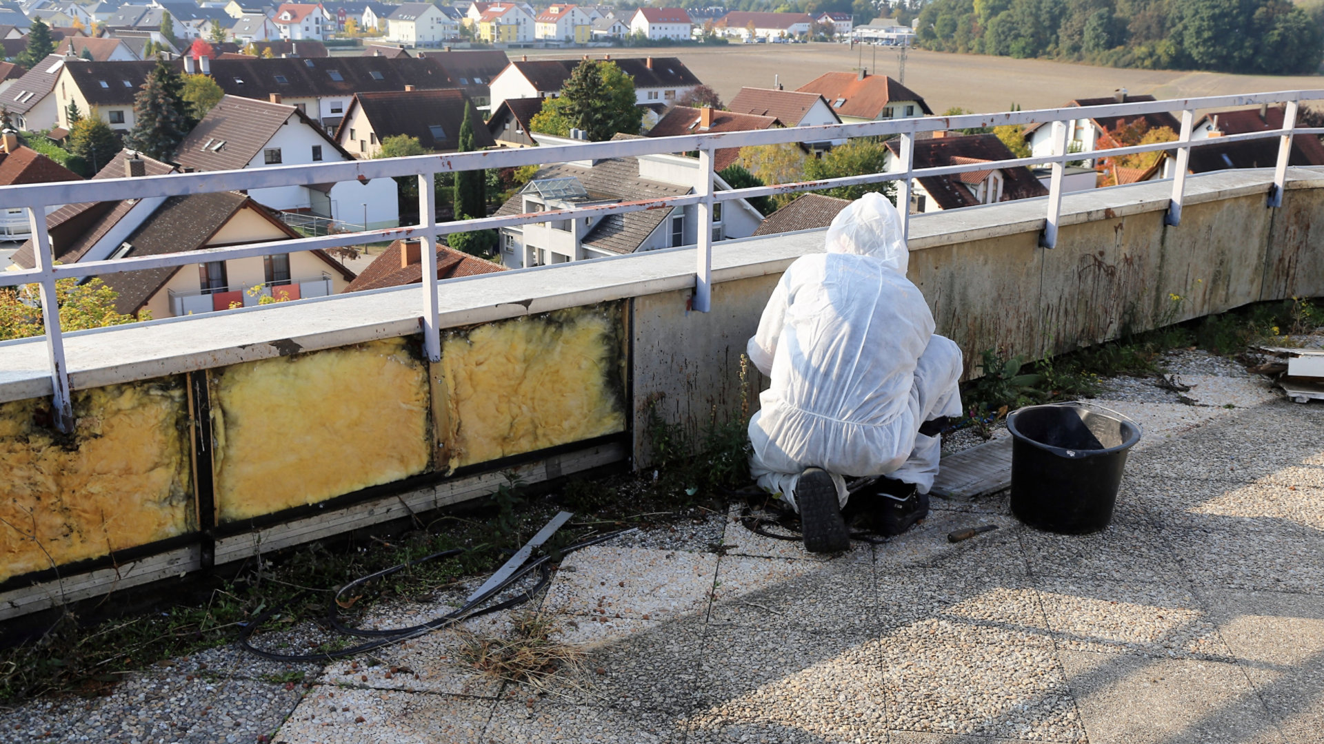 Man cleaning asbestos on a roof in a hazard suit.