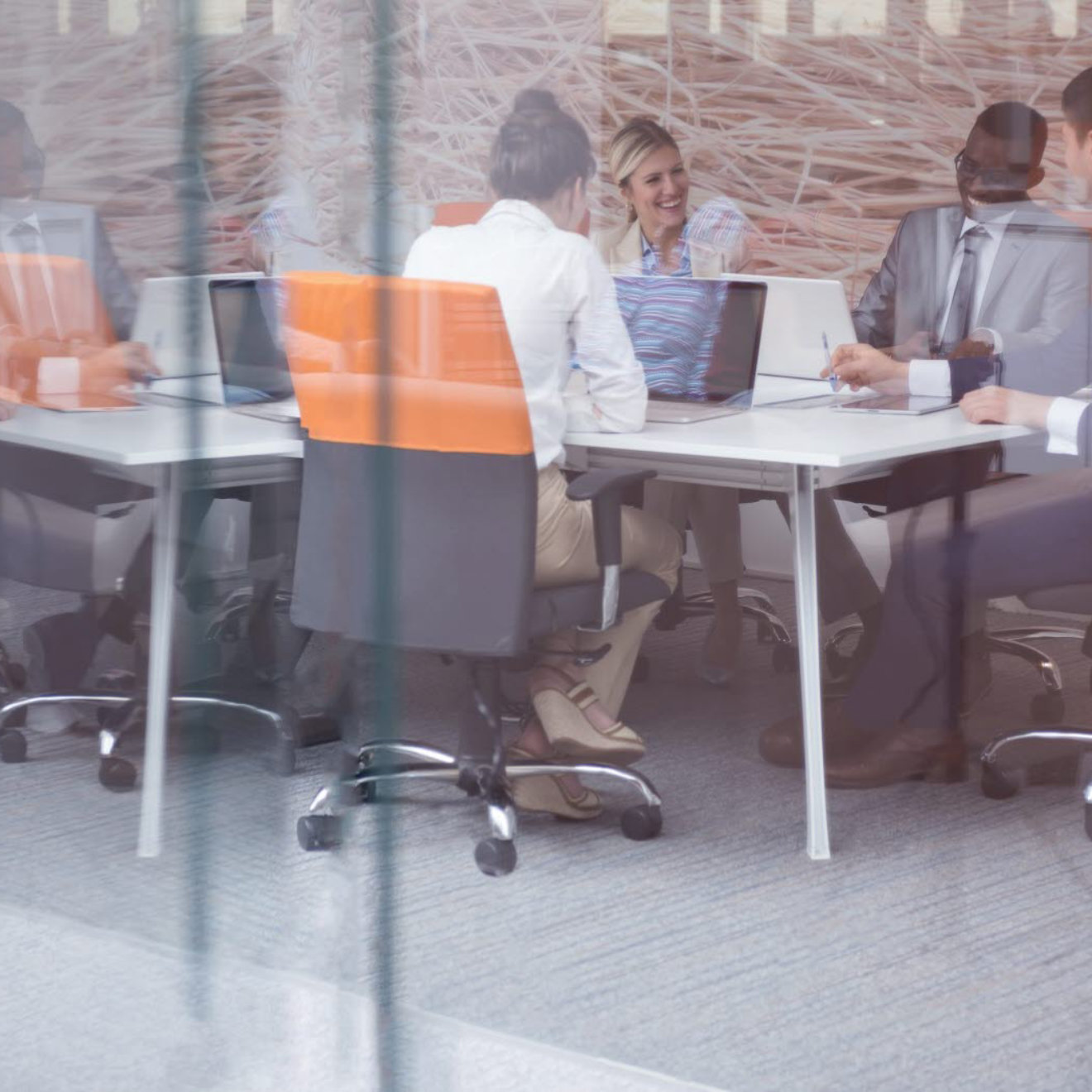 A business meeting taking place inside a glass-fronted meeting room