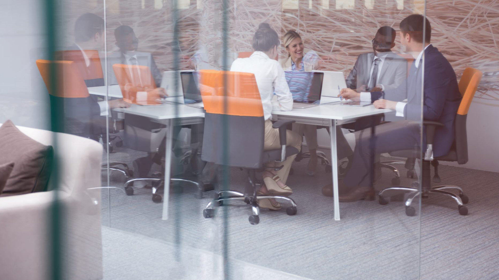 A business meeting taking place inside a glass-fronted meeting room