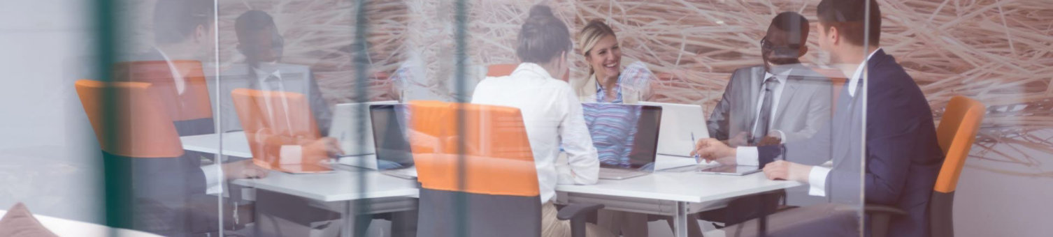 A business meeting taking place inside a glass-fronted meeting room