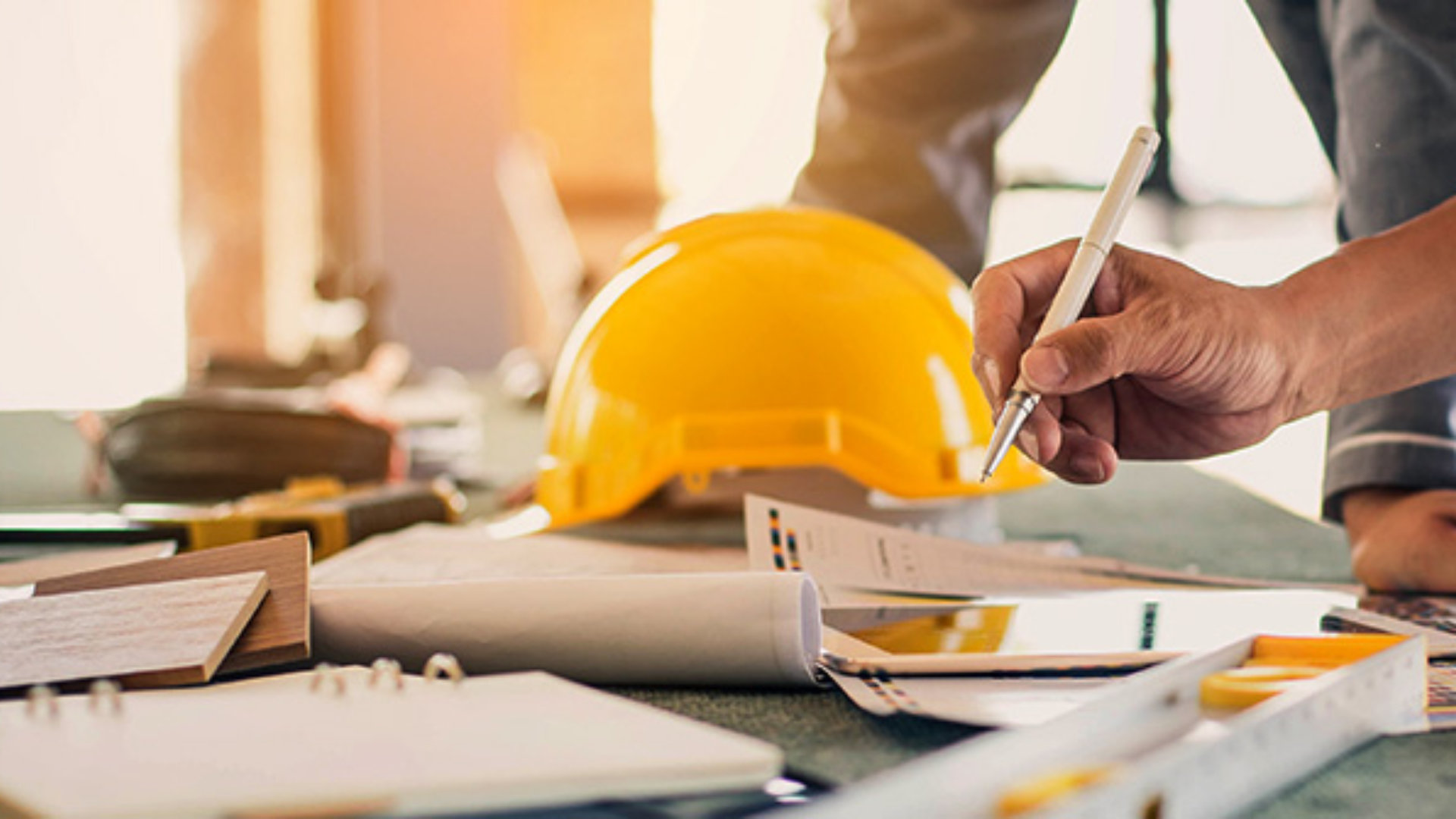 A trio of people on a construction site are looking at a blueprint