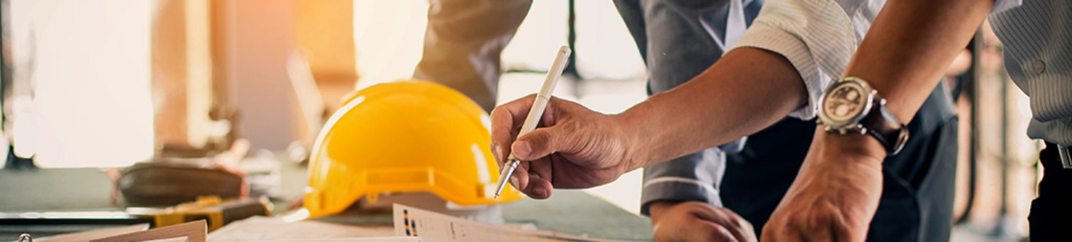 A trio of people on a construction site are looking at a blueprint