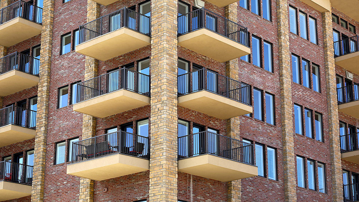 Side view of a new build red brick apartment complex with balconies