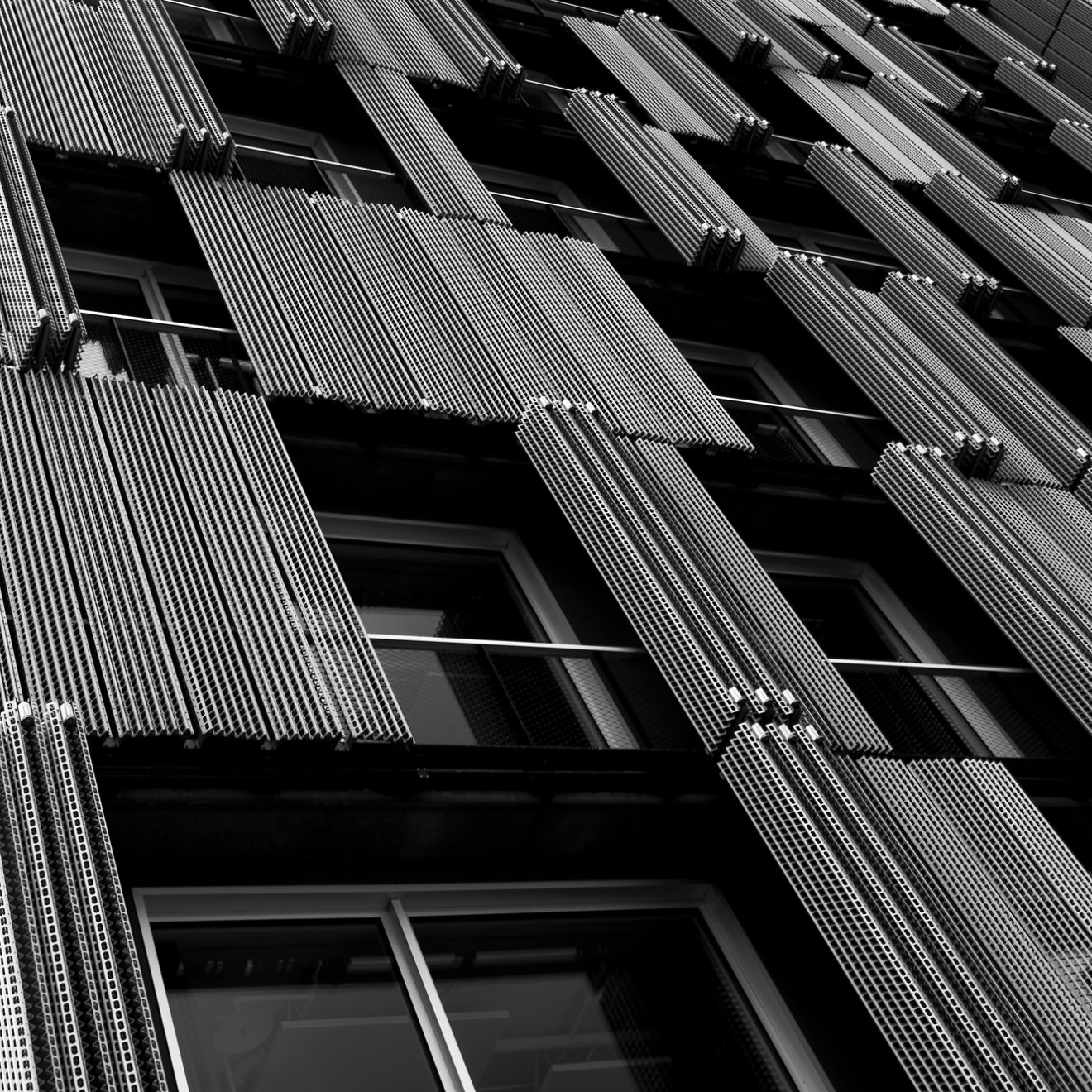 A black and white closeup of windows and cladding on a building