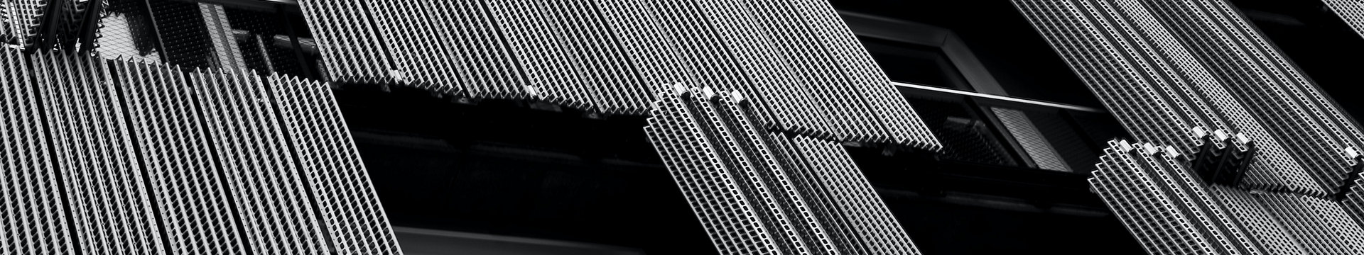 A black and white closeup of windows and cladding on a building
