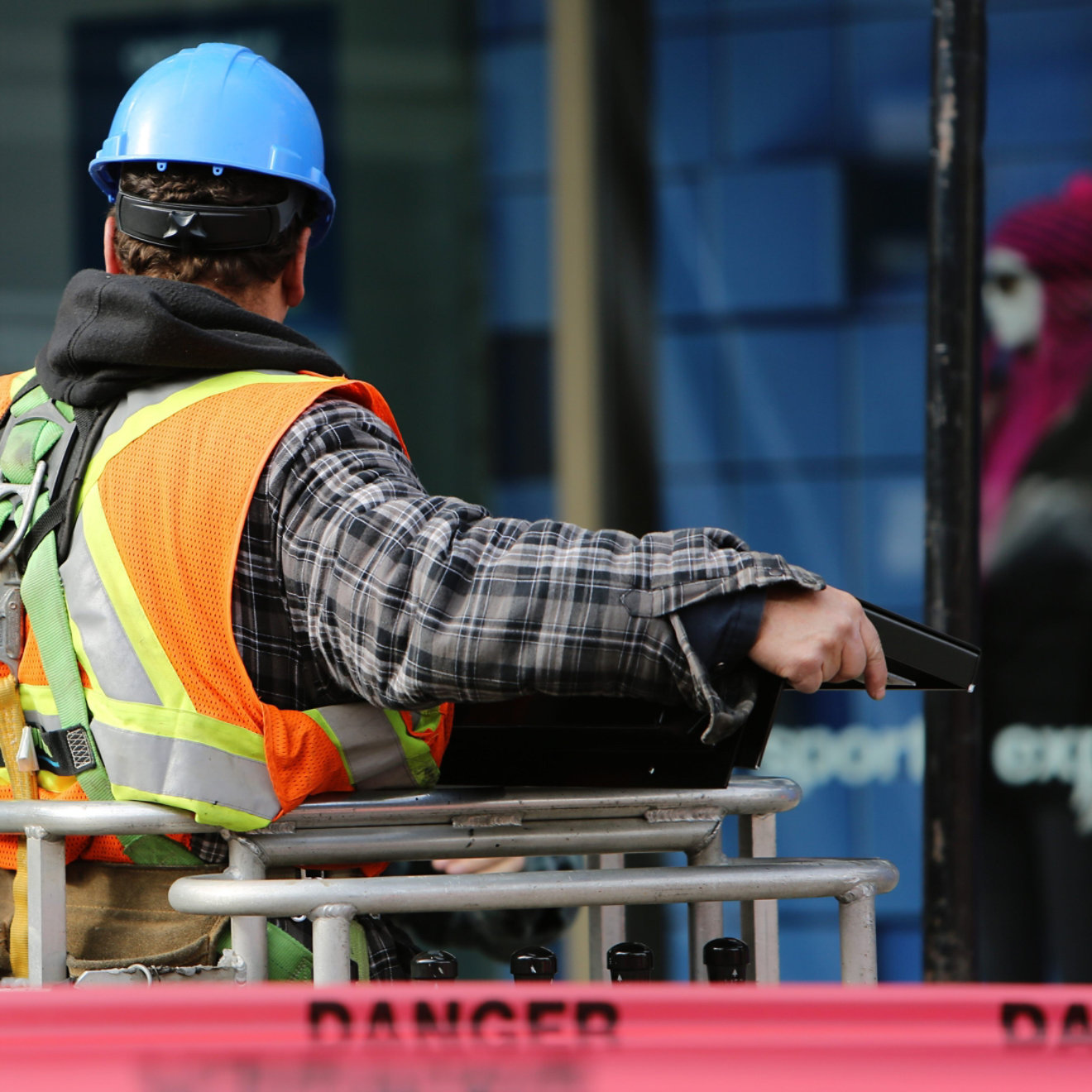 Construction worker in a hi-vis vest and harness operating winching equipment