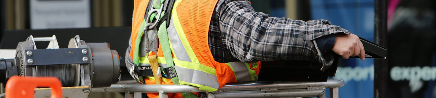 Construction worker in a hi-vis vest and harness operating winching equipment