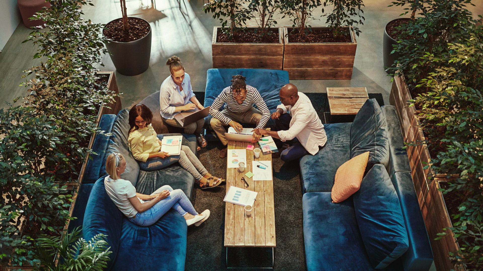 High angle of a group of diverse young businesspeople having a casual meeting together on sofas around a coffee table in an office lounge; Shutterstock ID 1622168197; Purchase Order: N/A