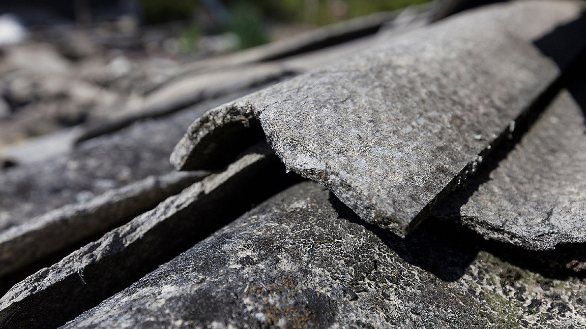 Close-up view of the broken and fibrous slice of corrugated asbestos cement sheets
