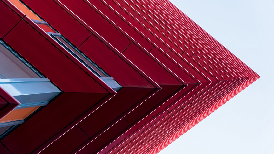 Detail of a red skyscraper set against a light blue sky
