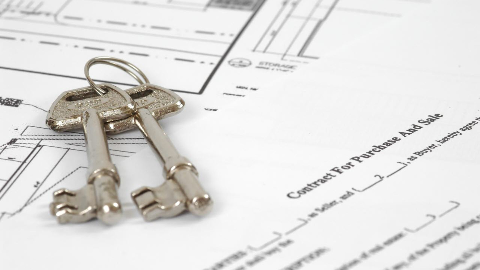 A pair of door keys resting on paperwork for a property sale