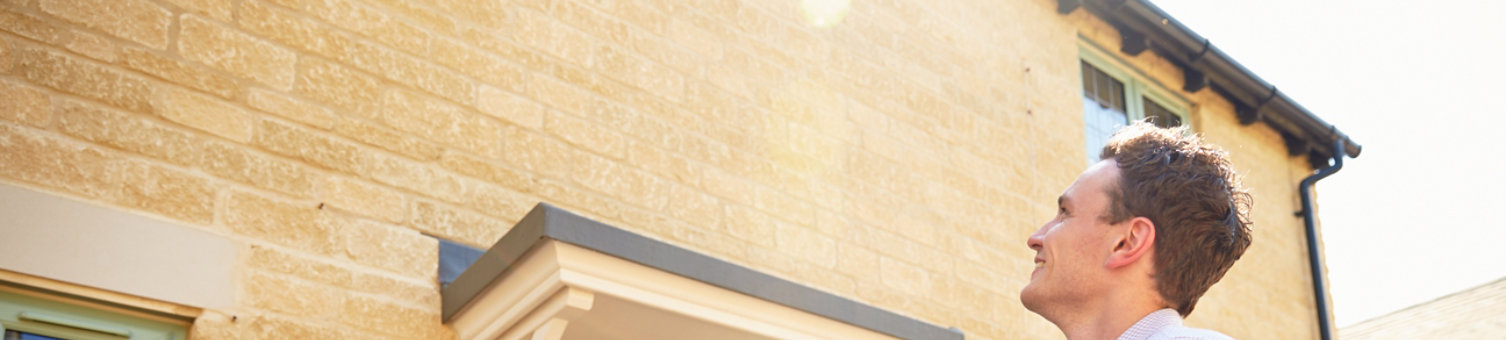 Male surveyor looking up at the exterior of a house