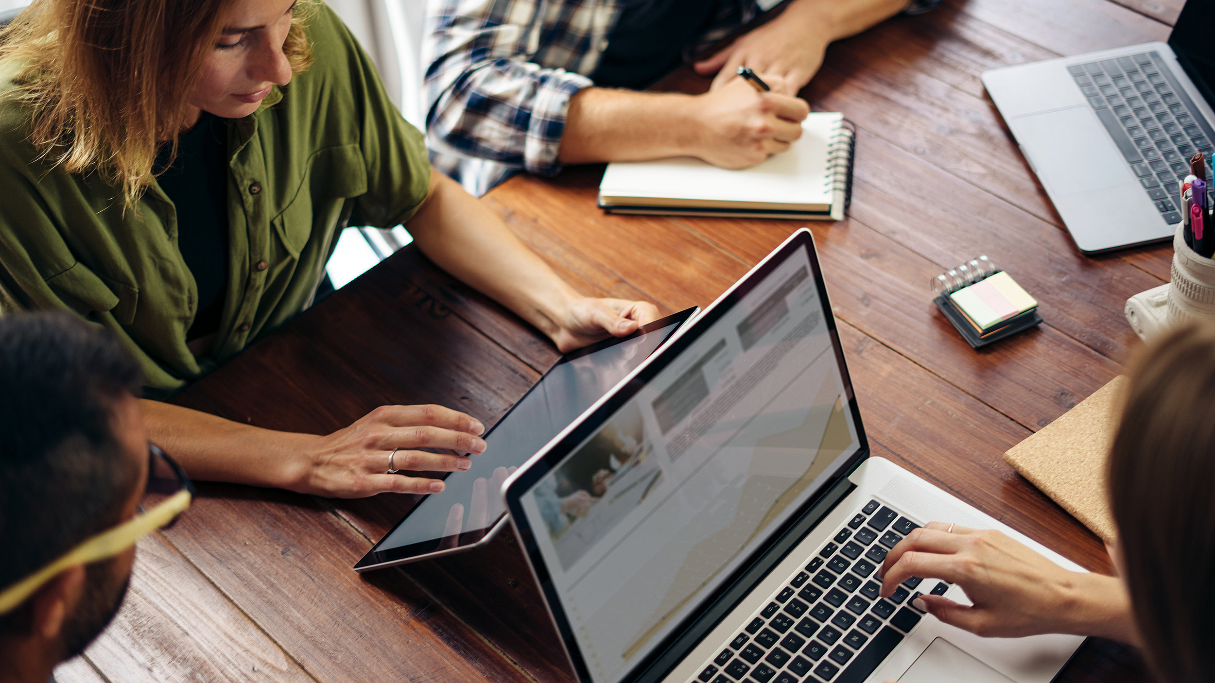 Group of people working together on laptops around a table in a modern office space