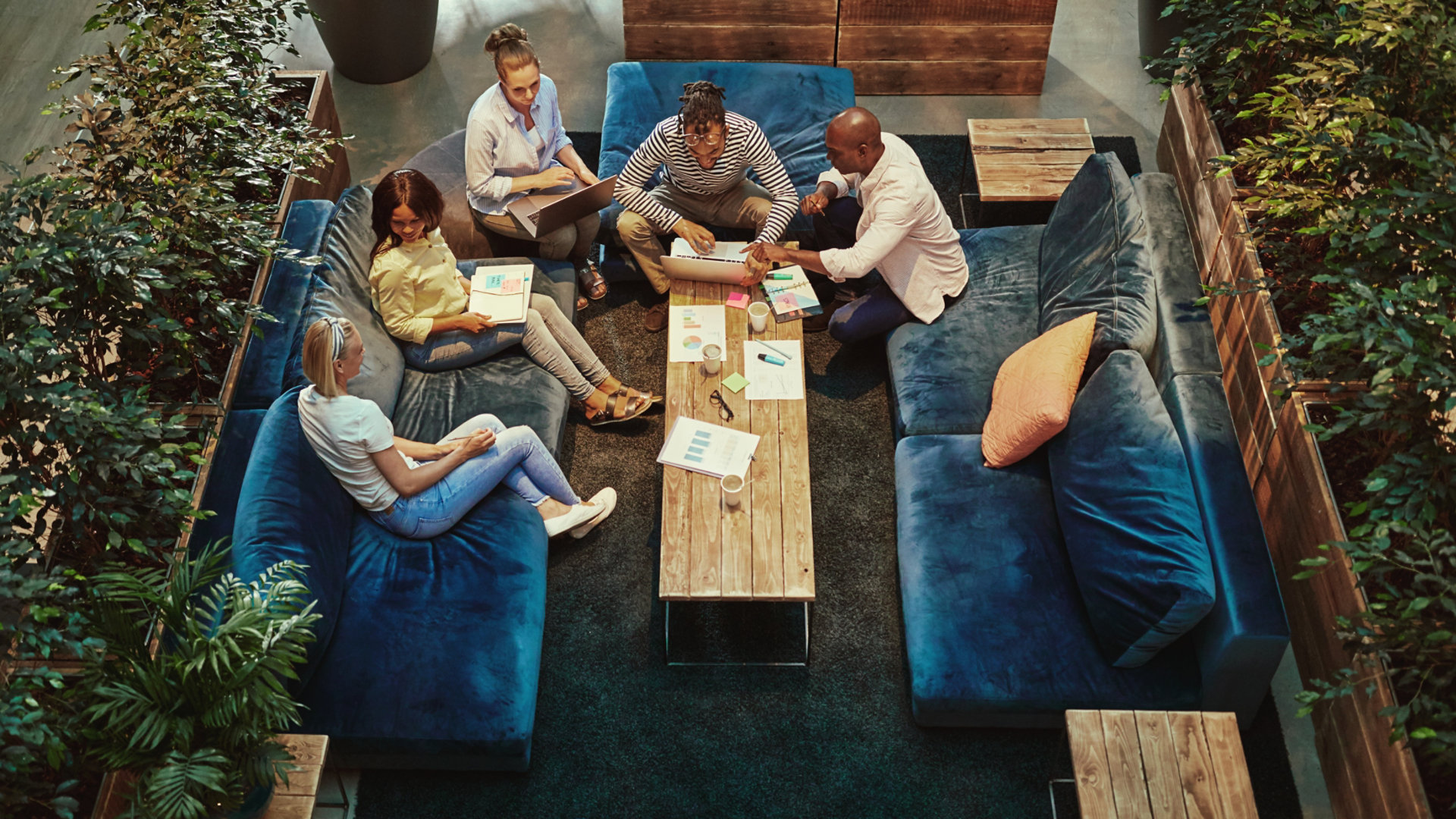 High angle of a group of diverse young businesspeople having a casual meeting together on sofas around a coffee table in an office lounge; Shutterstock ID 1622168197; Purchase Order: N/A