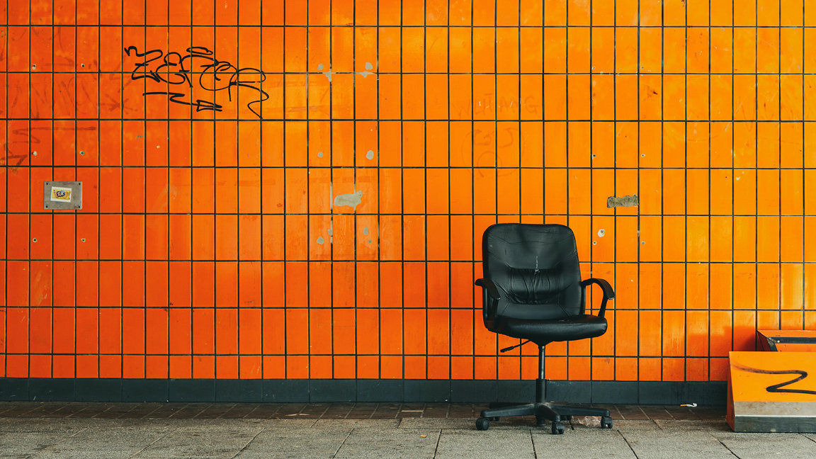 Photo of an office chair in front of an orange tiled wall.