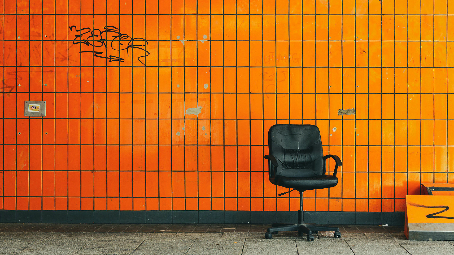 Photo of an office chair in front of an orange tiled wall.