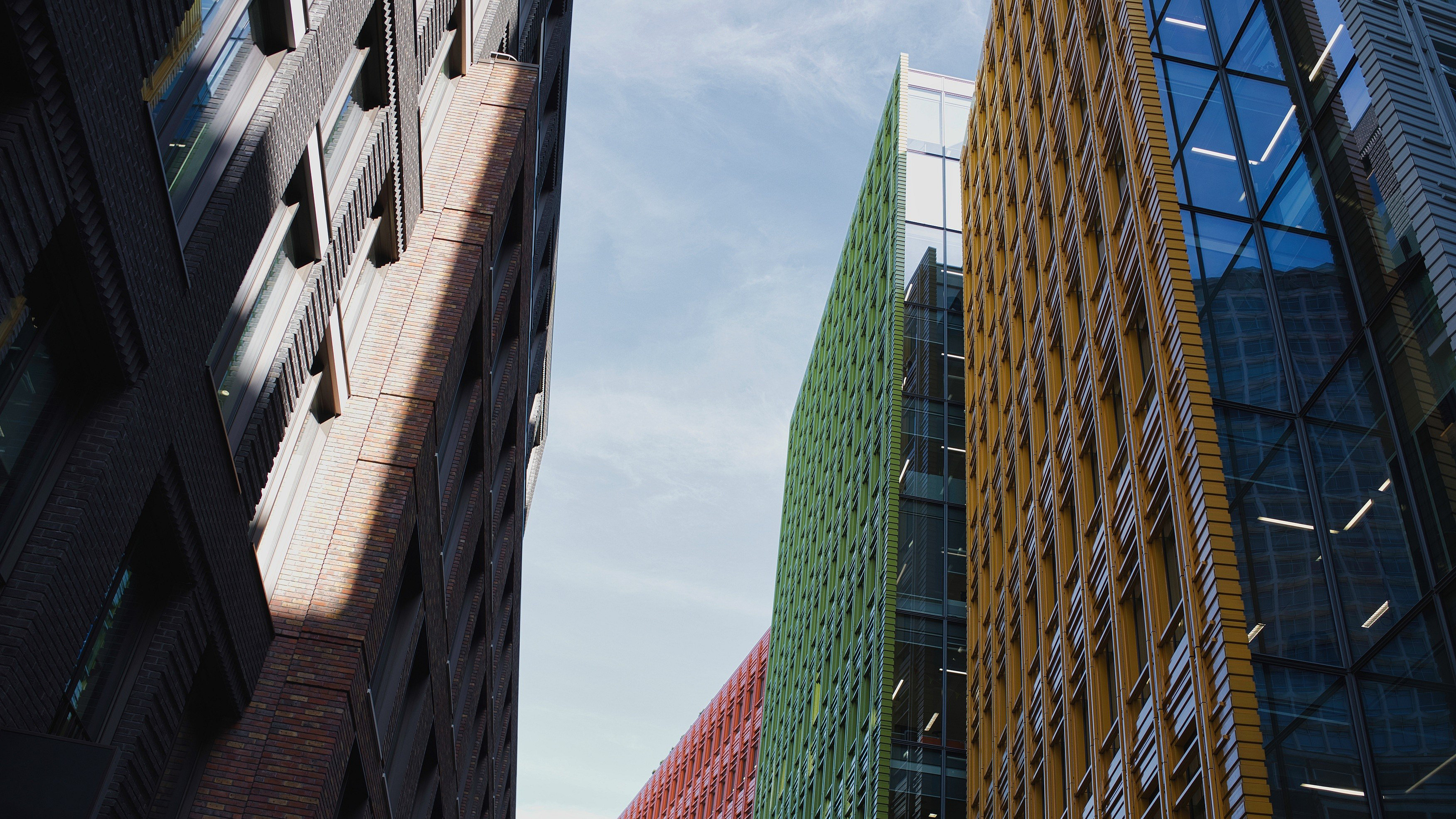 Modern architectural buildings standing tall against the blue sky, showcasing a dynamic urban landscape, blending diverse designs, textures, and vibrant colors in london city