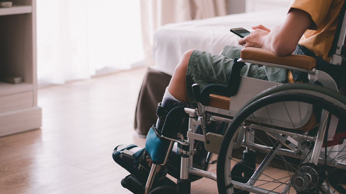 Young wheelchair user with a smartphone in a home setting