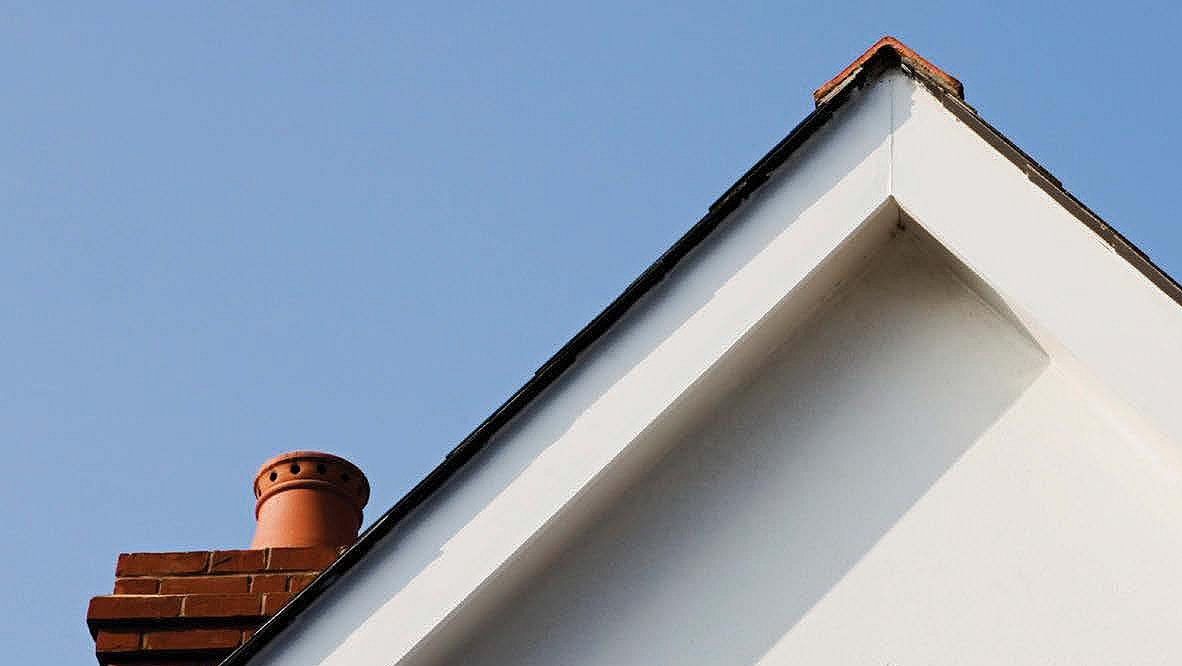 Roof and chimney against blue sky background