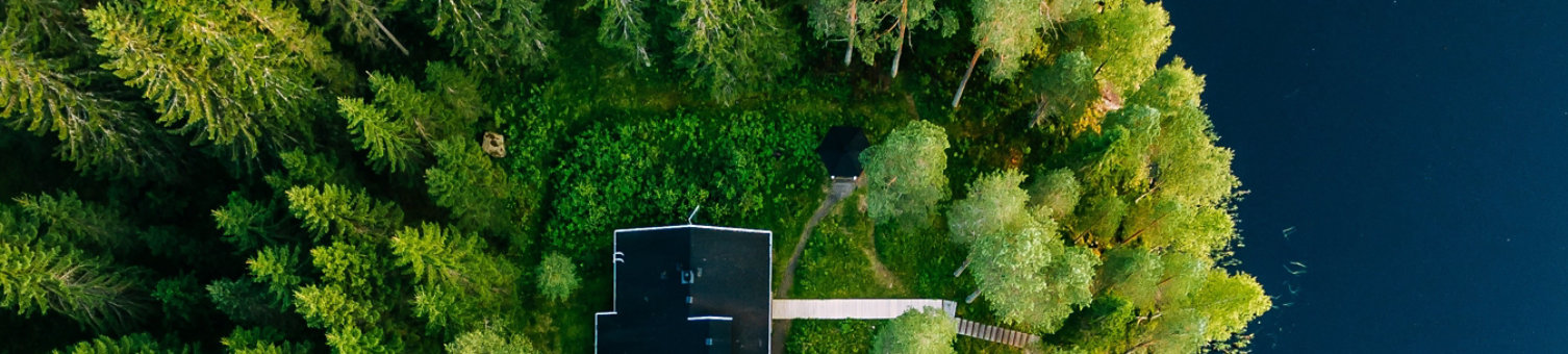 Aerial view of wooden cottage in green pine forest by the blue lake in rural summer Finland; Shutterstock ID 1106522063; purchase_order: -; job: -; client: -; other: -