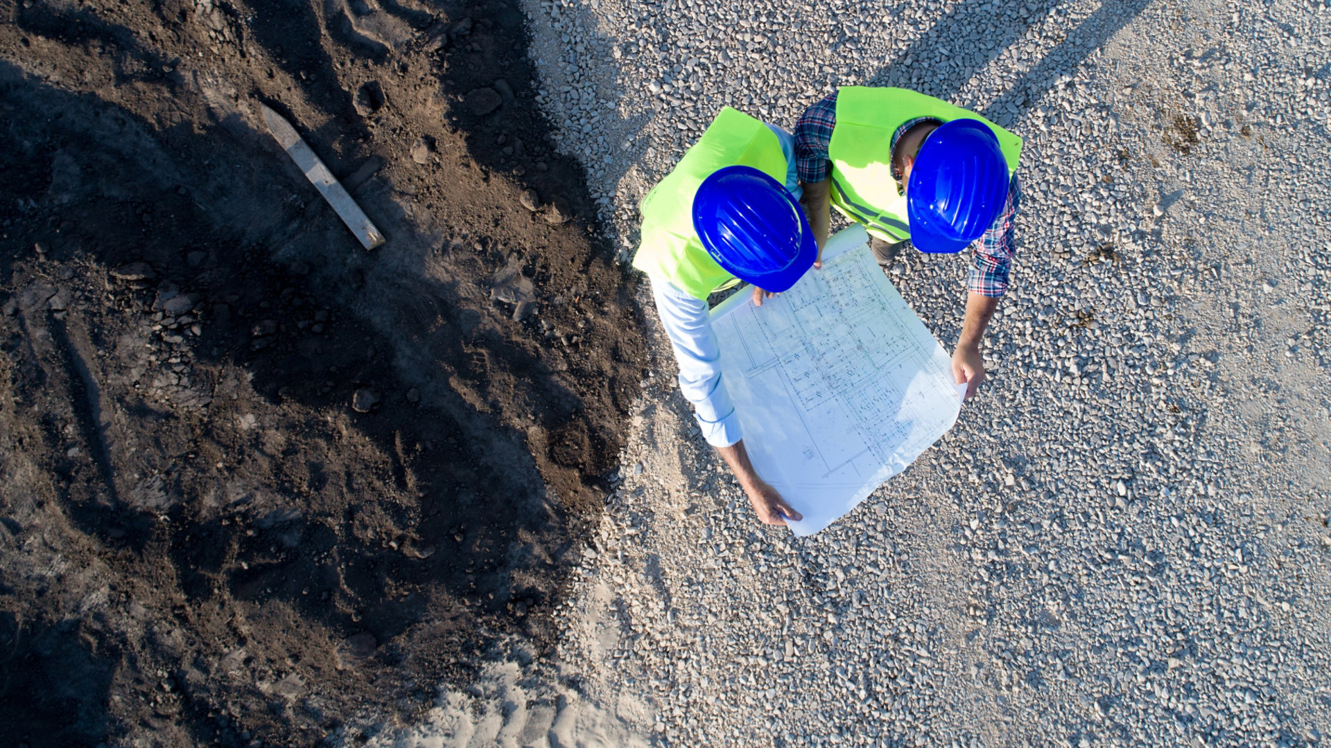 A surveyor looking at plans at a construction site as viewed from above