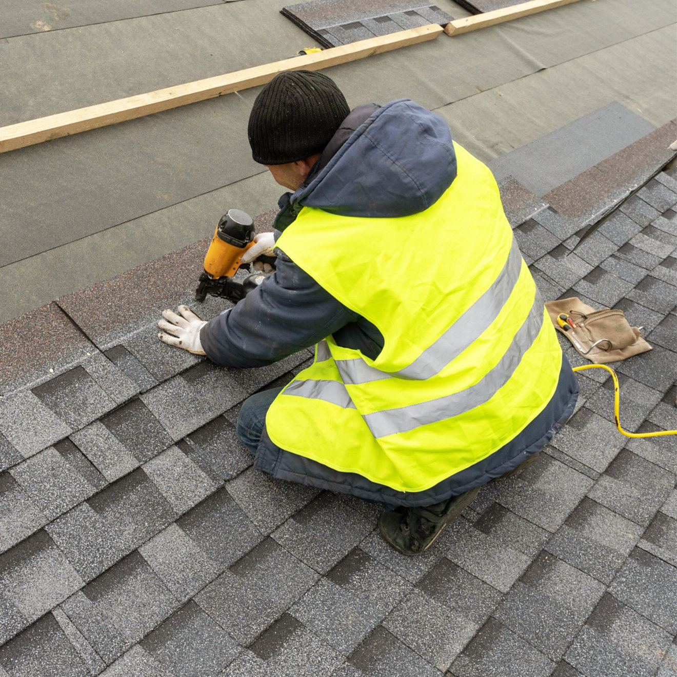 A man in a high-vis jacket working on a tiled roof
