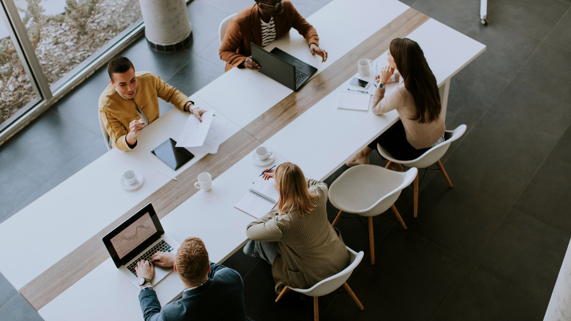 Aerial view at group of young multiethnic business people working together and preparing new project on a meeting in the office; Shutterstock ID 2131677027; purchase_order: -; job: -; client: -; other: -