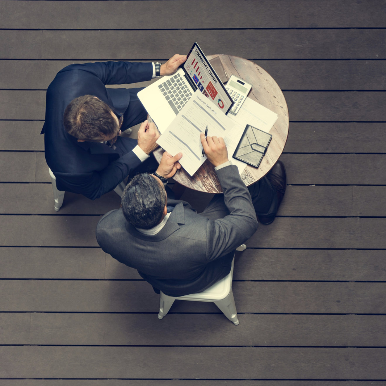 Two men at a desk signing documents as viewed from above