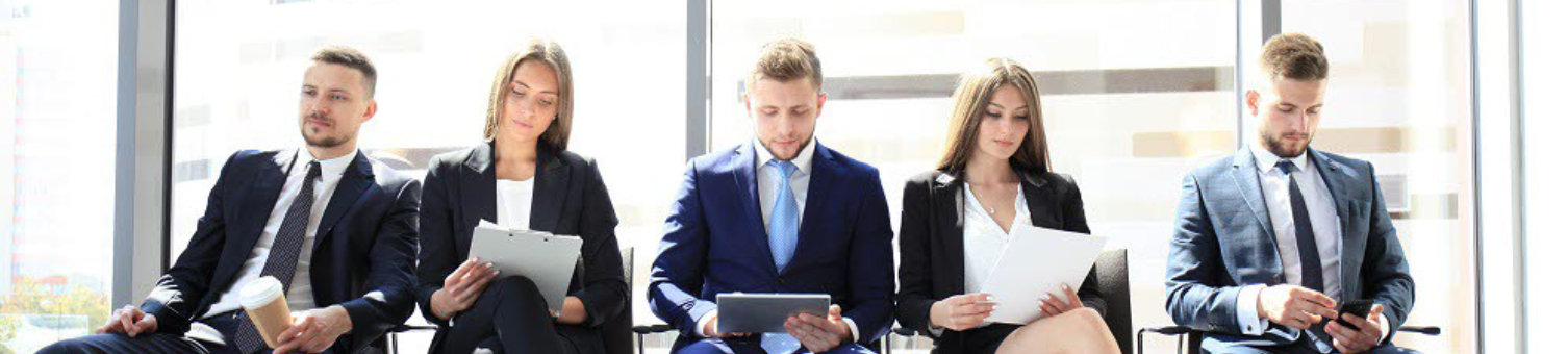 A group of interview candidates waiting on chairs in an office.