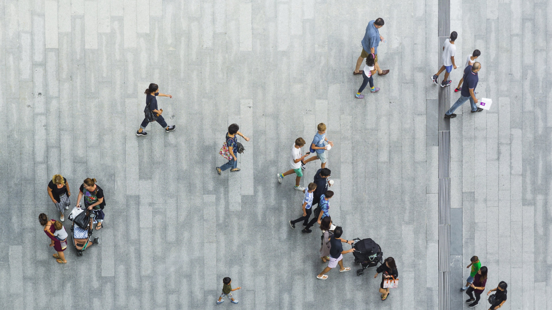 A moving crowd outside on a paved area as seen from above