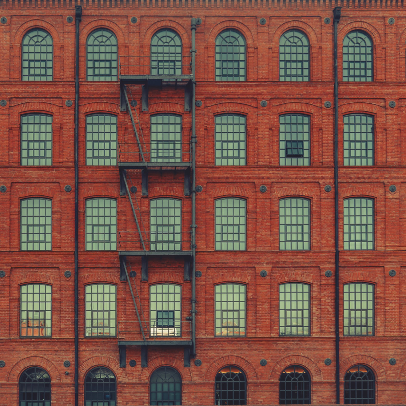 Huge red brick classic industrial building facade with multiple windows and fire escape ladder stairs. Industrial background. Loft inspiration. Construction facade concept. Vintage effect.; Shutterstock ID 642174928; purchase_order: -; job: -; client: -; other: -