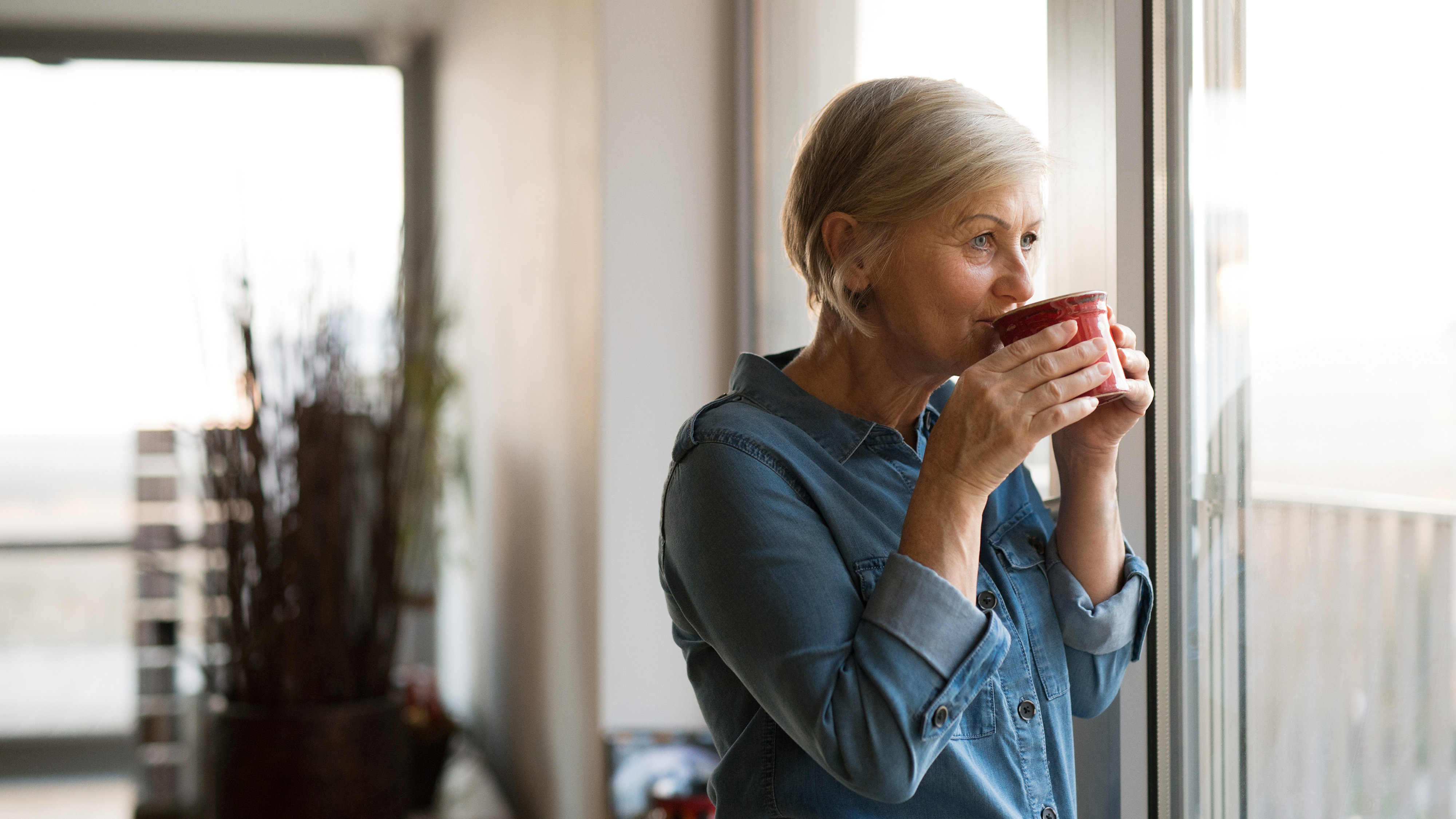 Senior woman at the window holding a cup of coffee