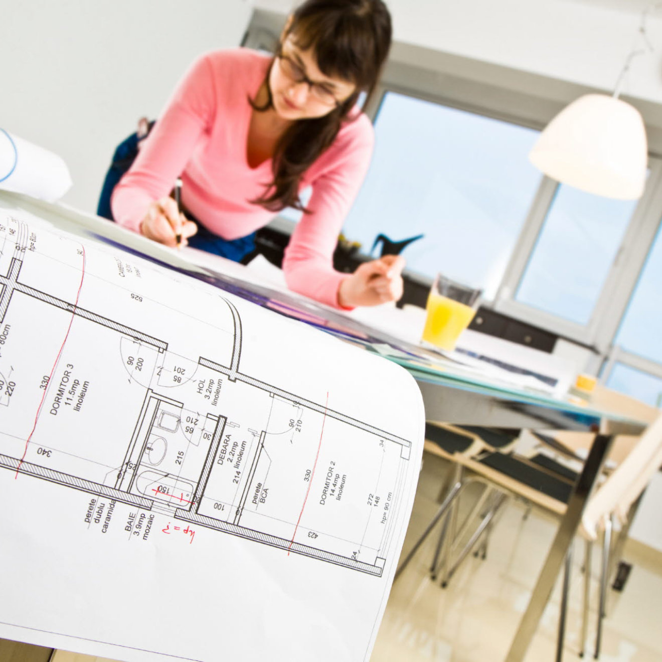 A woman at a drafting desk looking at blueprints