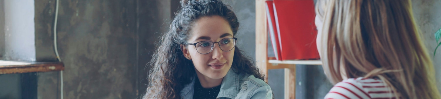 A younger professional woman talking to a colleague in an informal setting